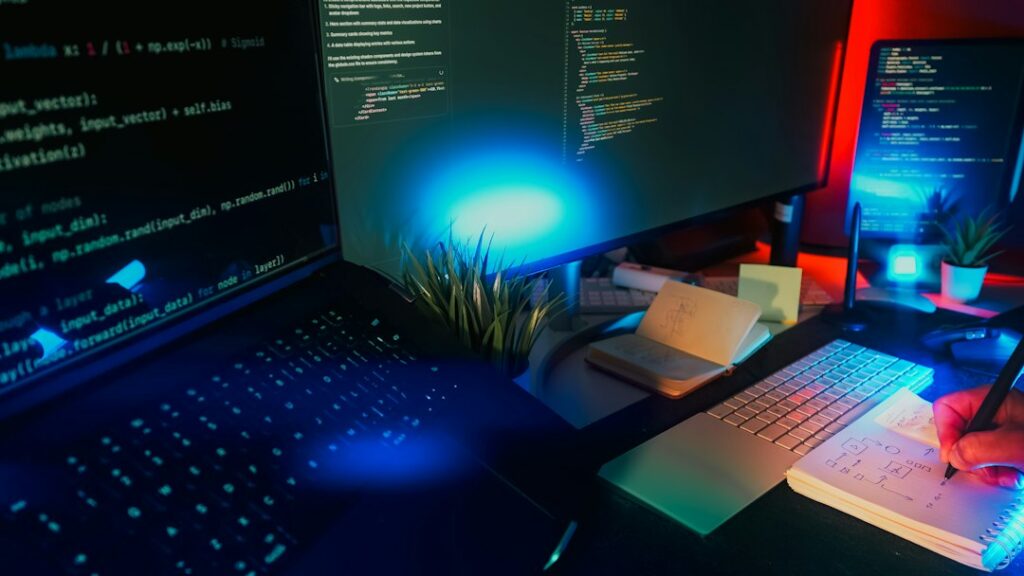 Developer workstation displaying source code on multiple monitors, illustrating AI-assisted game mechanics development