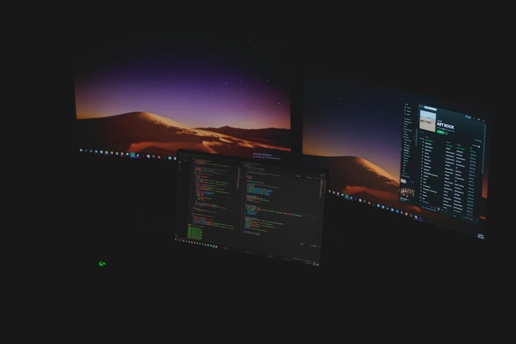 Dark workstation with multiple computer monitors showing software development tools