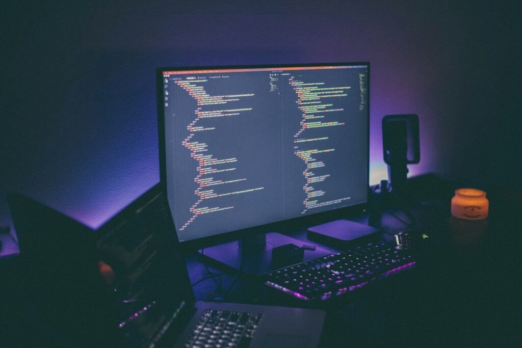 Developer desk with illuminated monitors showing code, representing AI-assisted game development
